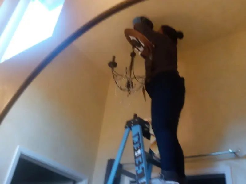 Electrician installing a chandelier in a Highland Park residence
